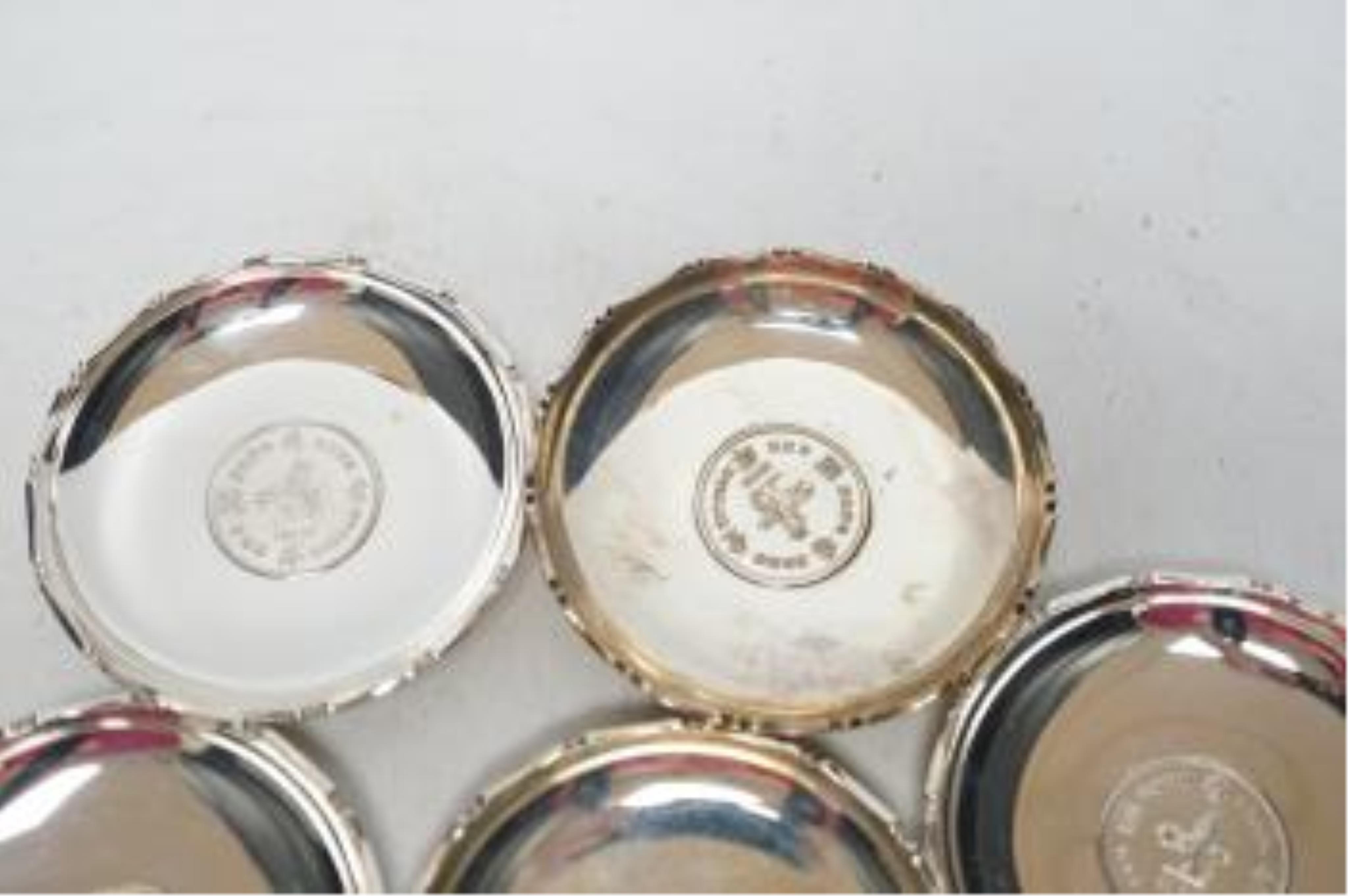 A set of seven Hong Kong sterling small dishes with inset coin, signed 'Sammy', diameter 86mm, gross weight 10.2oz. Good condition.